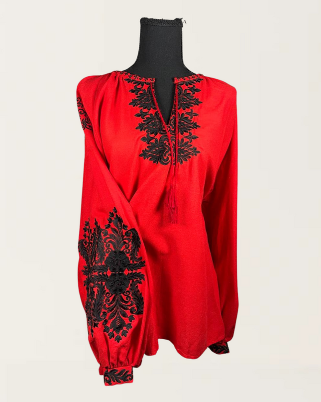 Red blouse with intricate black embroidery on the sleeves and neckline, perfect for stylish occasions.