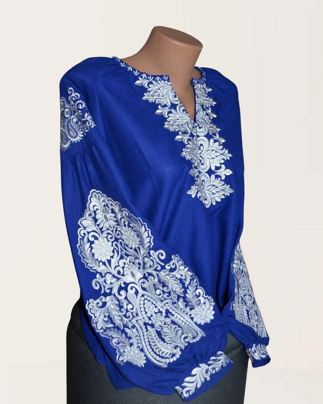 Blue blouse featuring intricate white embroidery on sleeves and front, perfect for casual or dressy occasions.